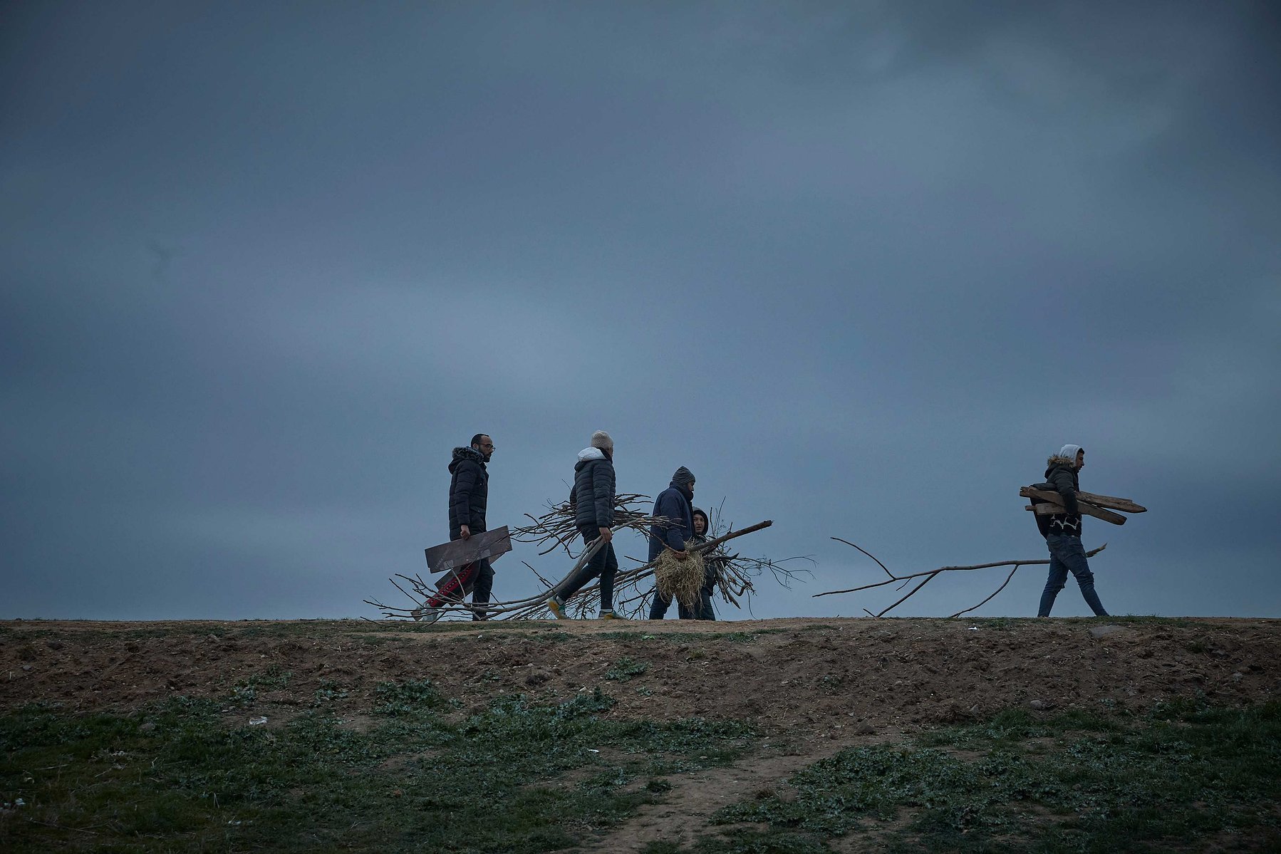 MARCH 5, 2020 - EDIRNE, TURKEY: Refugees carry firewood to their shelter in a makeshift camp on the banks near the Edirne Old Bridge as they wait to cross into Greece and the European Union on March 05, 2020 in Edirne, Turkey.