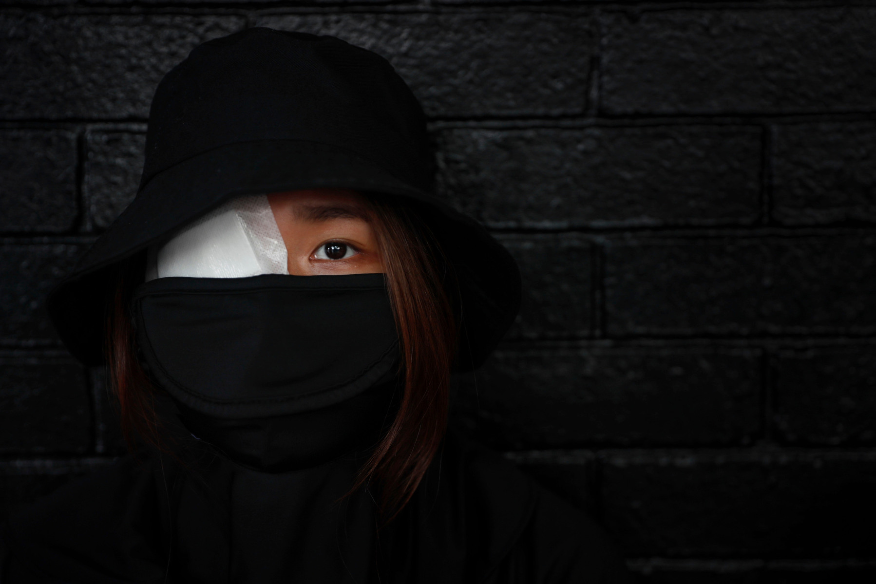 HONG KONG PROTESTS, HONG KONG - AUGUST 22, 2019: A pro-democracy protestor wearing an eye patch - a symbol to represent police brutality - takes a break from a demonstration amidst rising tensions in Hong Kong towards the government