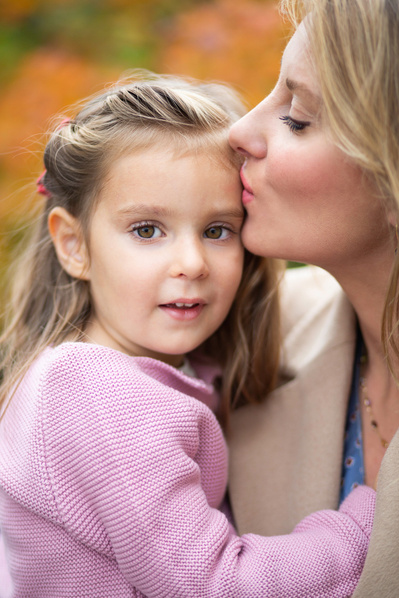 A Mum kisses her young daughter on the forehead in Southern England.
