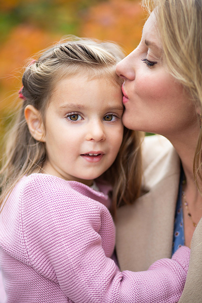 A Mum kisses her young daughter on the forehead in Southern England.