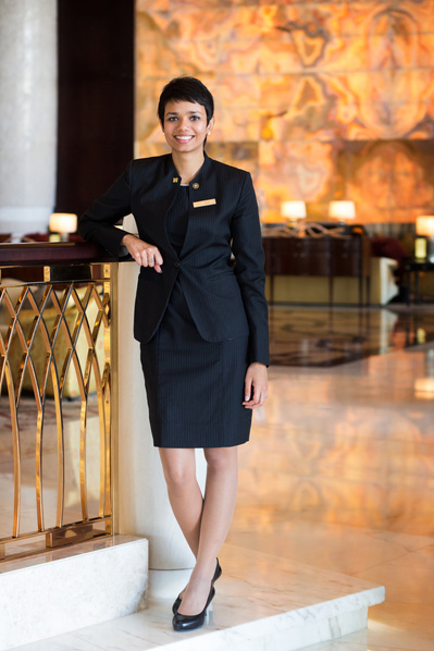 A hotel receptionist poses for a full length portrait in a five star luxury hotel in Dubai.