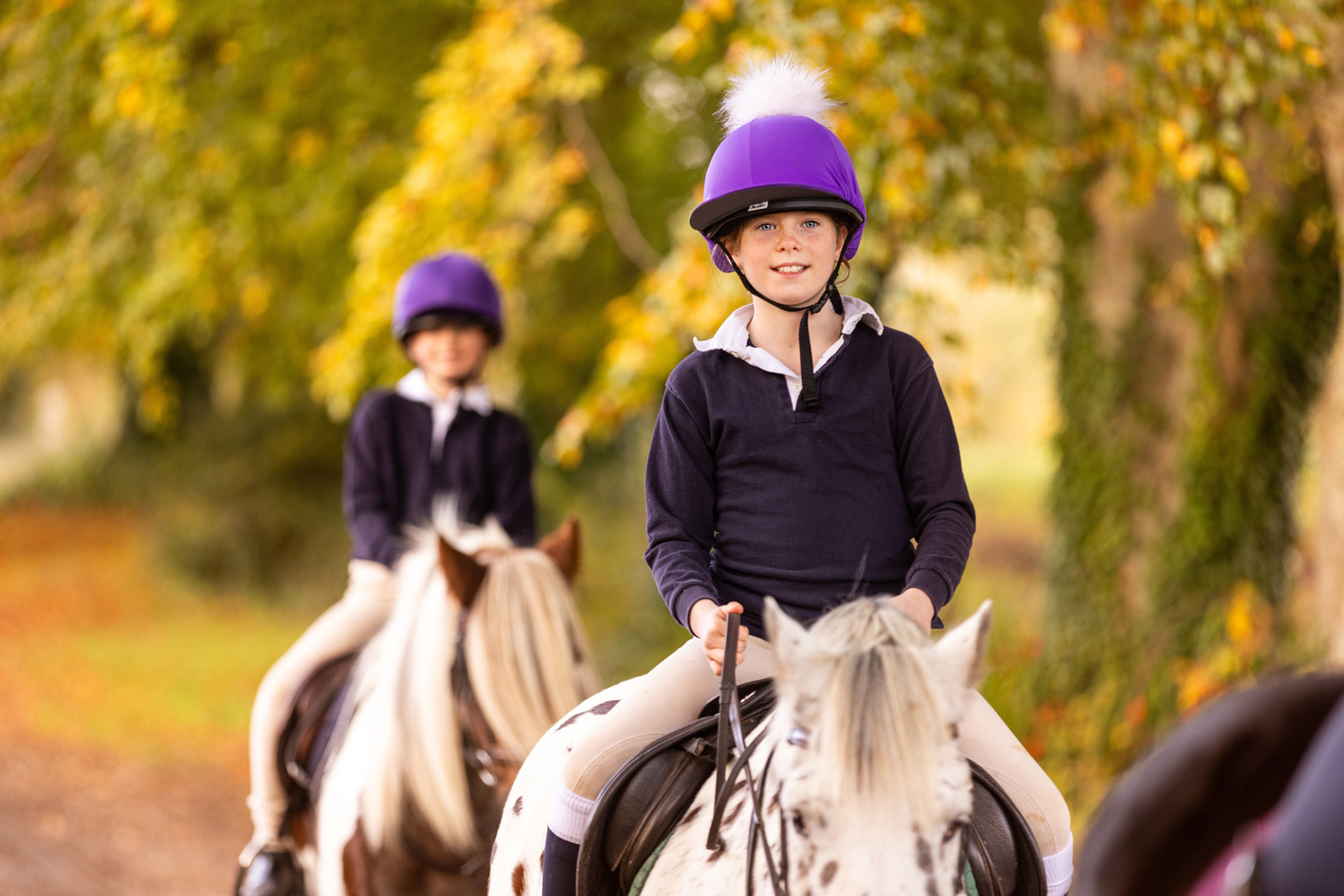 Two girls riding ponies at school in dorset
