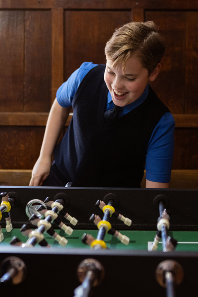 A pupil at Sunningdale, Ascot, Berkshire plays table football in school uniform.