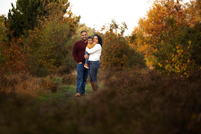A couple hold their son in a family portrait. They are in Holt Heath Nature Reserve.