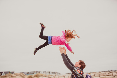 A 5 year old girl is being thrown in the air by her Father at Hengistbury Head, Bournemouth, Dorset