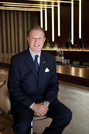 The general manager of a five star hotel in London sitting at a bar stool in his hotel's bar.