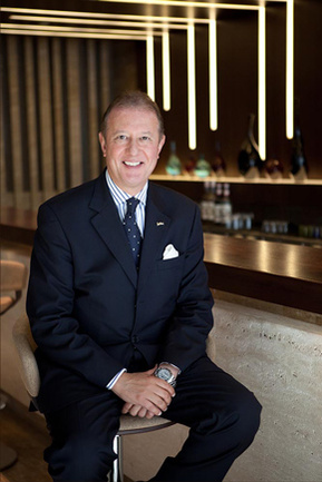 The general manager of a five star hotel in London sitting at a bar stool in his hotel's bar.