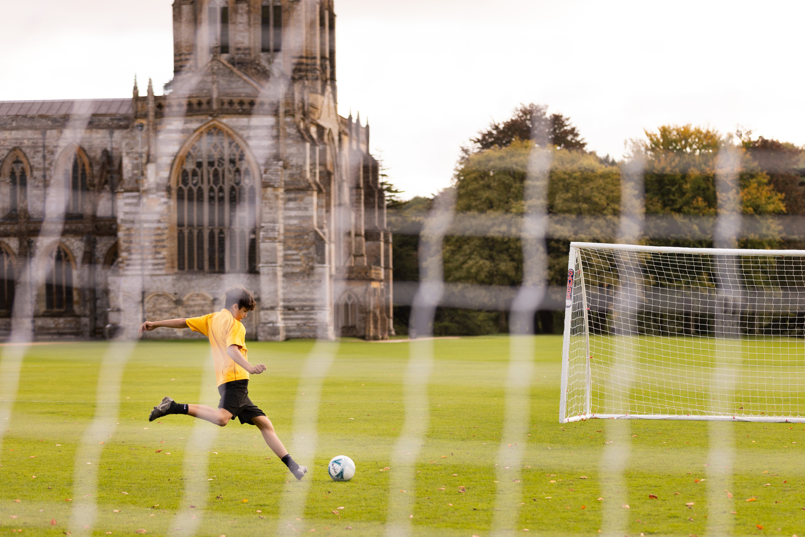 Boy playing football at Milton Abbey School in Dorset, an independent senior school.