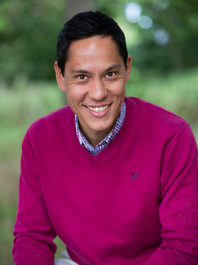 Corporate portrait of a smiling man in a pink jumper. He is outside at Upton Country Park, Dorset.