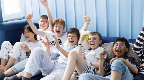 A group of boys cheer as their football team wins at Sunningdale School, Ascot. They are watching TV in their pyjamas.