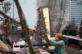 artist and craftswoman in her studio making, dwarfed by her creations, making  handmade timeless pieces out of vines
