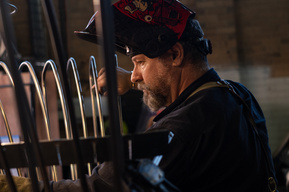 a man in a welding hat with a steel frame in a workshop