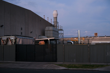 Factory infrastructure with pipelines , fence in the front and big  factory building and blue sky at dusk