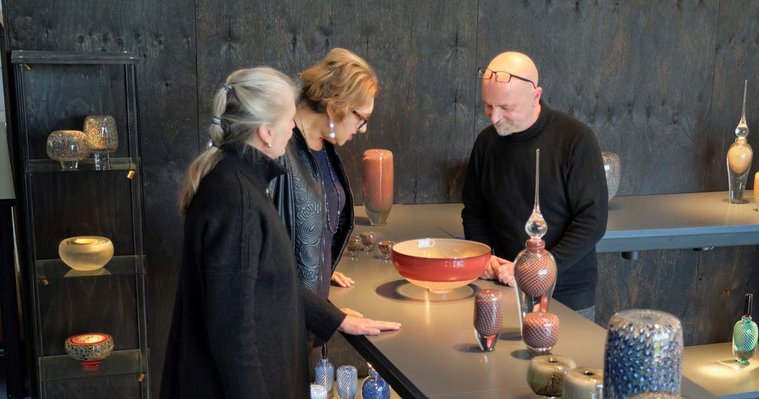 Anne (left) and Peter (right) show a customer (centre) some of their glass artwork on display in Glass Manifesto's Glass Gallery and Studio. 