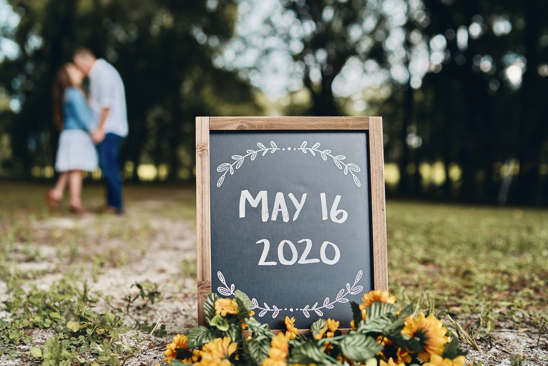 Couple embrace in the background with date of their wedding in the foreground.