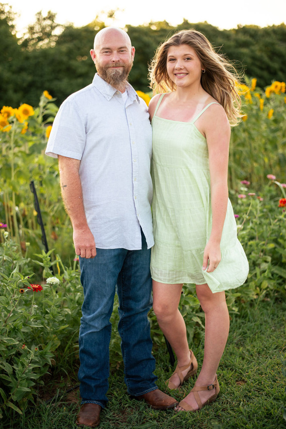 A father and his teenage daughter pose in front of a flower field in rural Oklahoma at sunset
