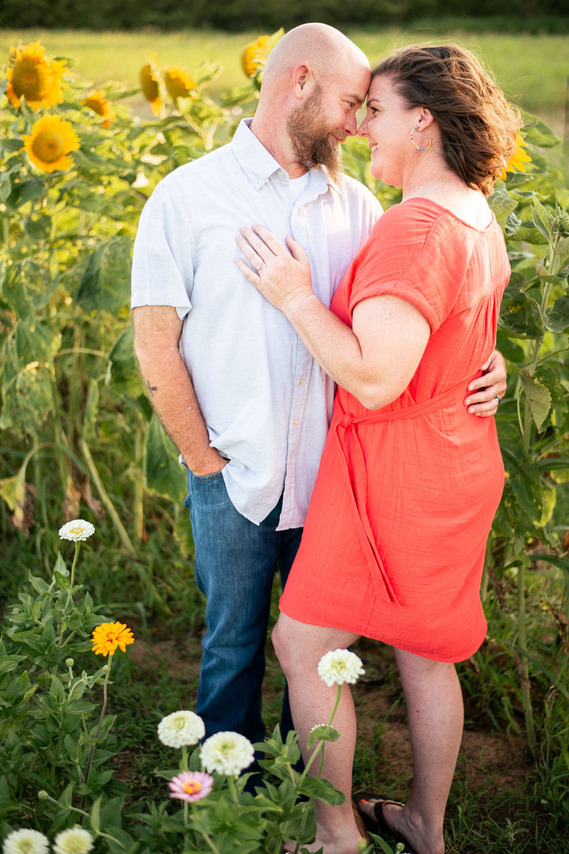 A husband and wife pose in front of a flower meadow at sunset in Oklahoma