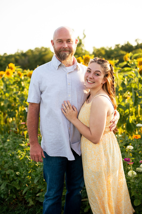 A father and his teenage daughter pose in front of a flower field in rural Oklahoma at sunset