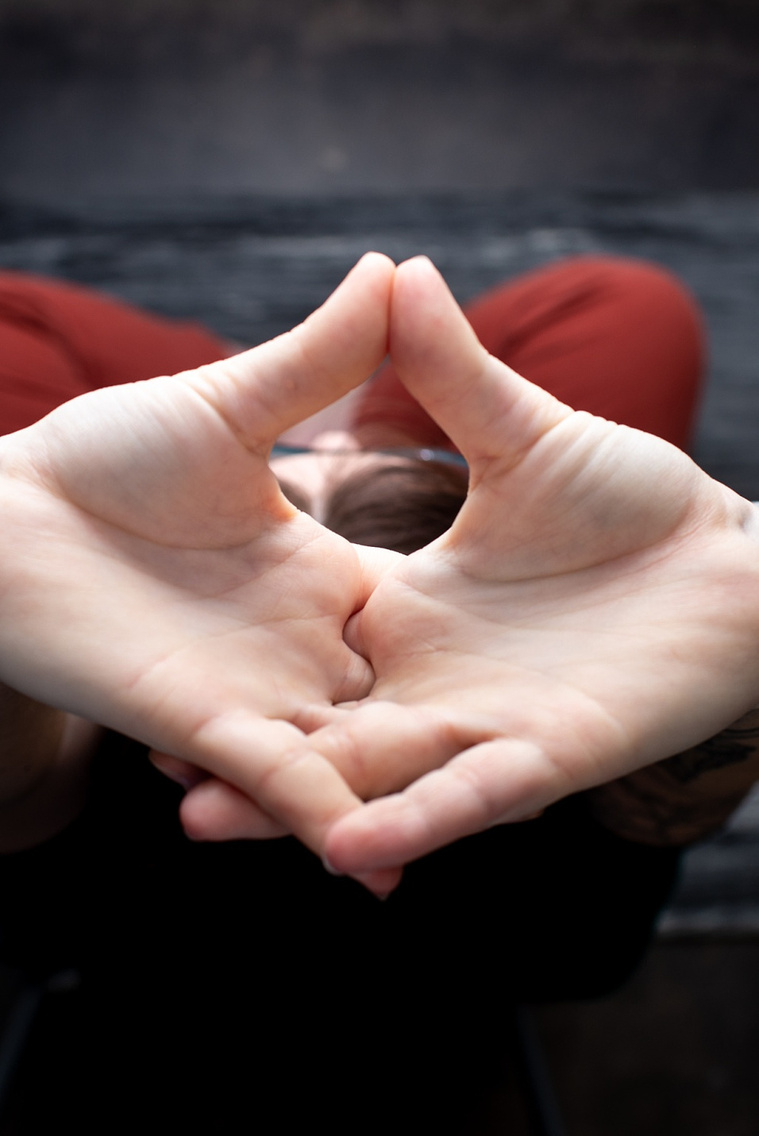 looking from above and close up of a woman doing a yoga pose with her hands straight up and down towards her crossed legs on a yoga mat at a branding session at Vibe Beauty Bar in Tuttle, Oklahoma