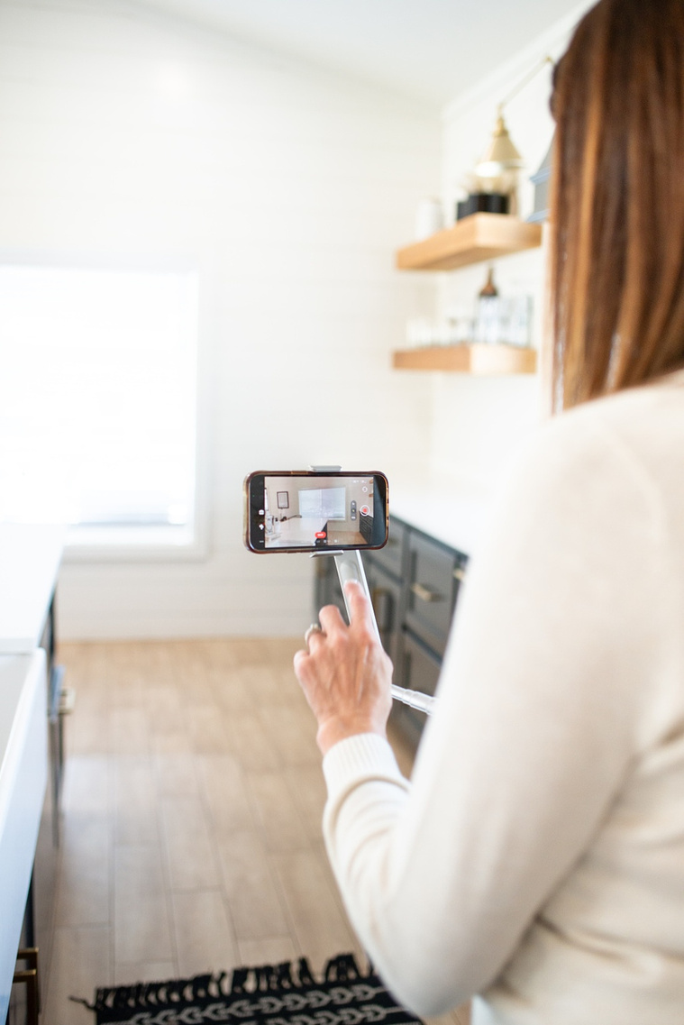 Brand photo shoot of realtor in OKC. She uses a gimbal to virtually tour clients through a home space in the kitchen