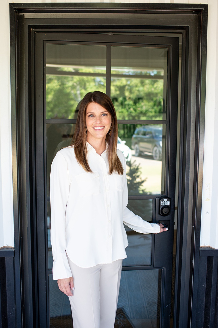 Brand photo shoot of realtor in OKC. She smiles opening the entry door to show clients a home.