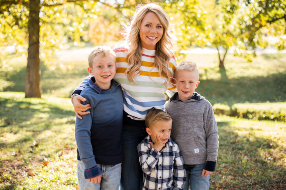 a mom hugs together with her three young sons at Will Rogers Park in Oklahoma City, Oklahoma at a fall photo mini session by Cheryl Jackson Photography