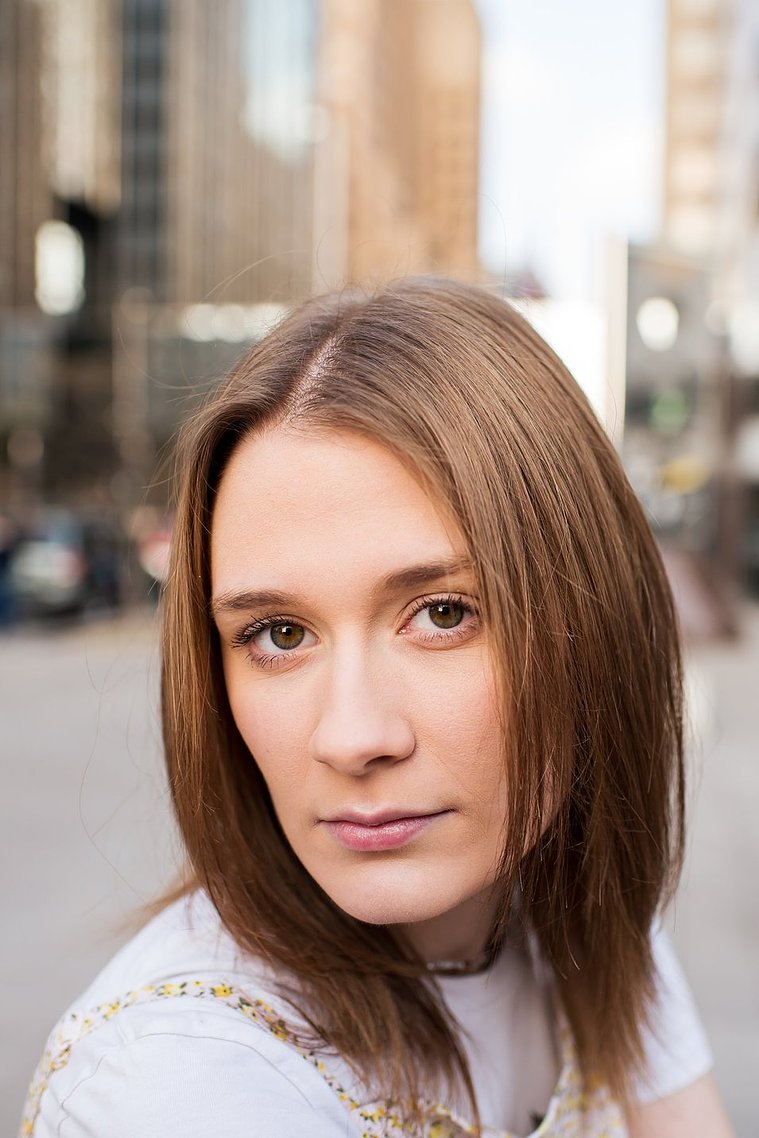 close up portrait of a high school senior girl looking over her shoulder with a serious expression on a sidewalk in downtown Oklahoma City