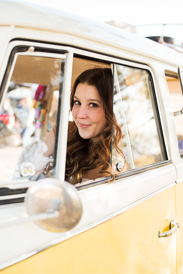 senior photo of a cute girl with long brown hair sitting in a yellow and white VW bus looking through the open window and smiling in Oklahoma