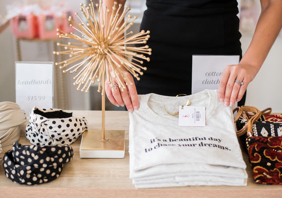 a small business shop owner places a t-shirt for display at her branding  photo session in Oklahoma City