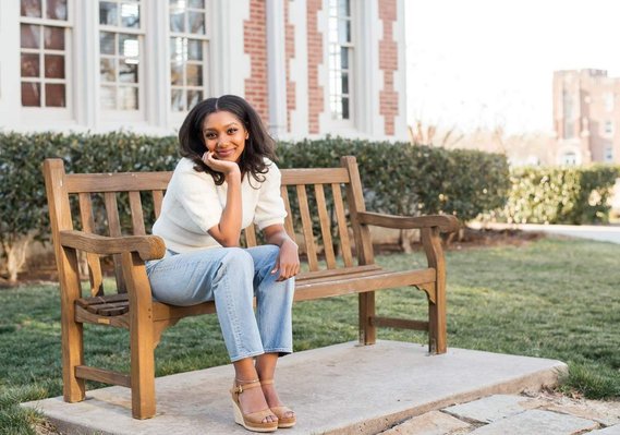 Senior girl sits on a bench at the OU campus in Norman, Oklahoma and poses for her senior portrait session