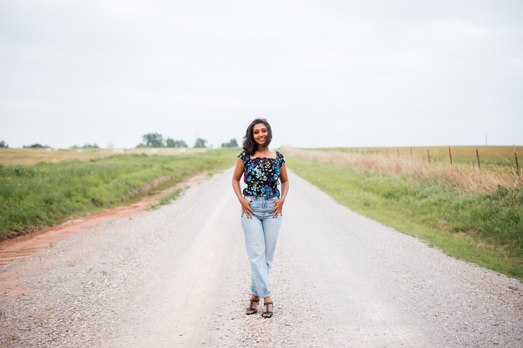 Senior girl poses in the middle of a gravel road in Oklahoma for a country photo session