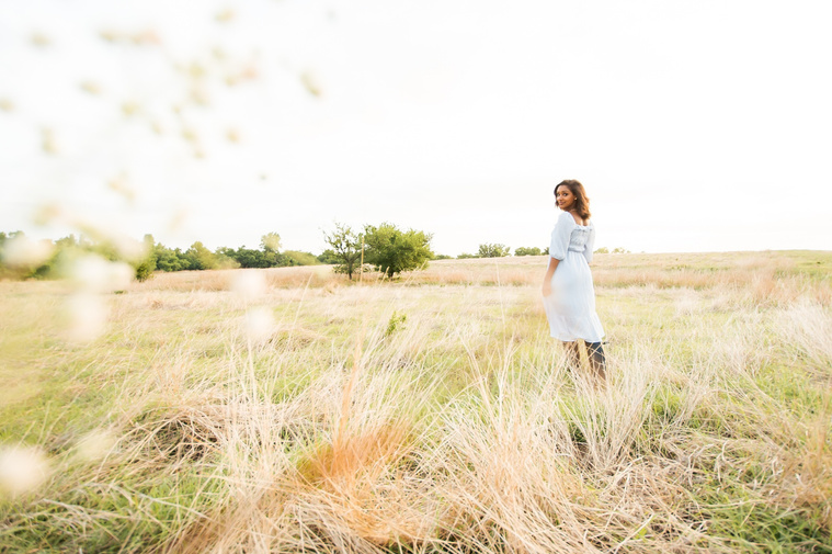 Senior girl poses in a golden field in Oklahoma for a country photo session