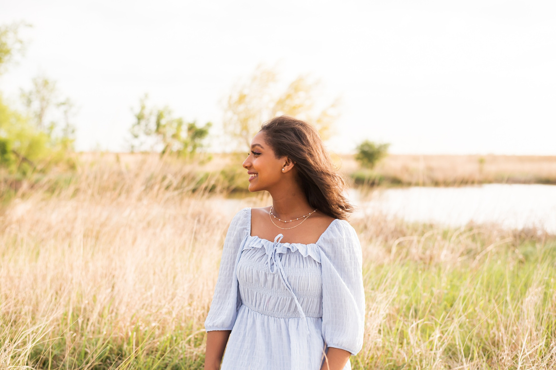 Senior girl poses in a golden field in Oklahoma for a country photo session