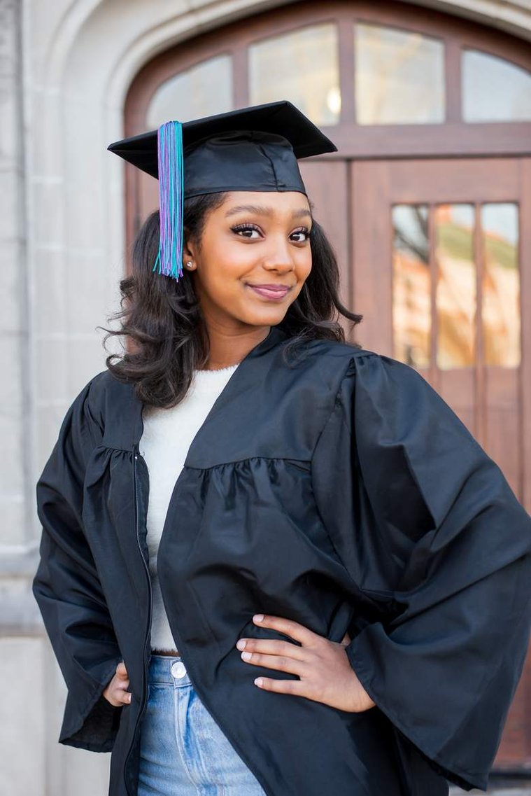 African-American teenage girl poses in her cap and gown on OU campus and smiles at her senior photo shoot in Norman Oklahoma