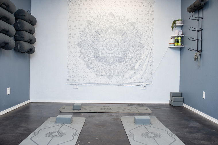 photo of a room for yoga class with yoga mats and blocks on the floor and extra mats hanging on walls at a branding session at Vibe Beauty Bar in Tuttle, Oklahoma