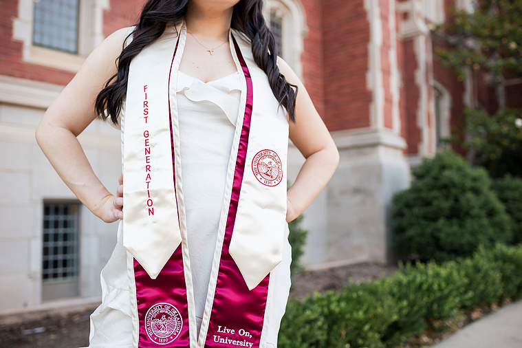 close up shot of a university of oklahoma graduation stole on a college senior girl with hands on hips, standing in front of Bizzell Library on OU campus in Norman