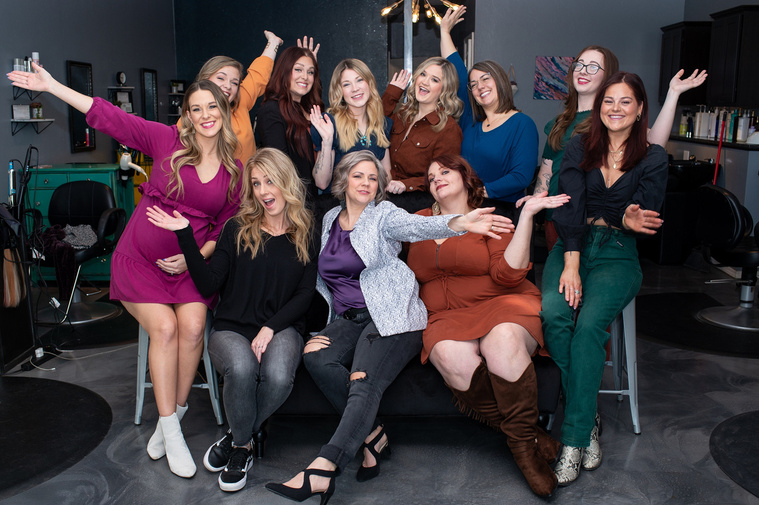 Team photo of cosmetologists throwing their hands up in a fun way inside a hair salon at a branding session at Vibe Beauty Bar in Tuttle, Oklahoma