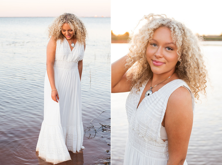 vertical portrait of a high school senior girl in a white flowy dress standing in the water swishing her skirt looking down and another of her with one hand in her hair smiling on the shore of Lake Hefner in Oklahoma City