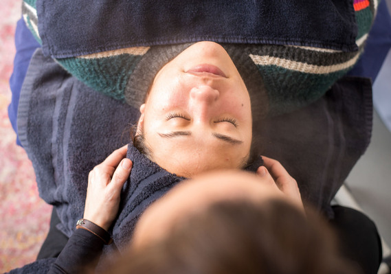 overhead shot of an aesthetician tucking a towel around her client's head as she prepares for a facial at a salon in Moore, Oklahoma