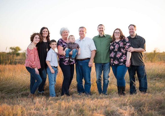 Large group multi-generational family photo in a field in the country at sunset