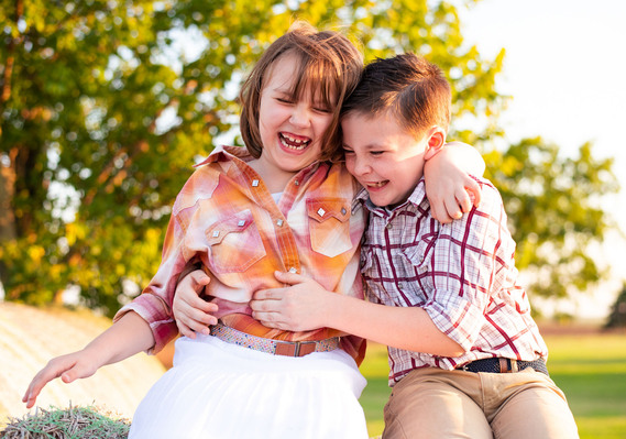 A brother and sister laugh while he tickles her stomach in a back to school photo session in Tuttle, Oklahoma