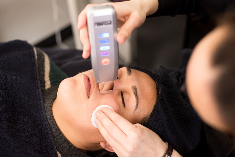 brand photo of an aesthetician at work on her client, taken from above showing the tool she is using close-up to do a facial at a salon in Moore, Oklahoma
