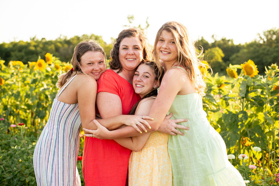 A mother and her three teenage daughters pose in front of a flower field in rural Oklahoma at sunset