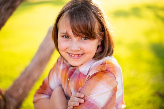 A little girl smiles with her arms crossed at her back to school photo session in the country in Oklahoma