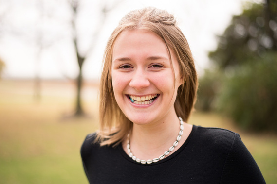 Portrait of a teenage girl in a black t-shirt in a park smiling 