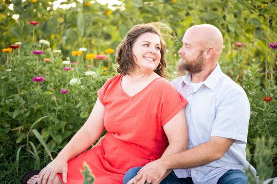A husband and wife pose in front of a flower meadow at sunset in Oklahoma