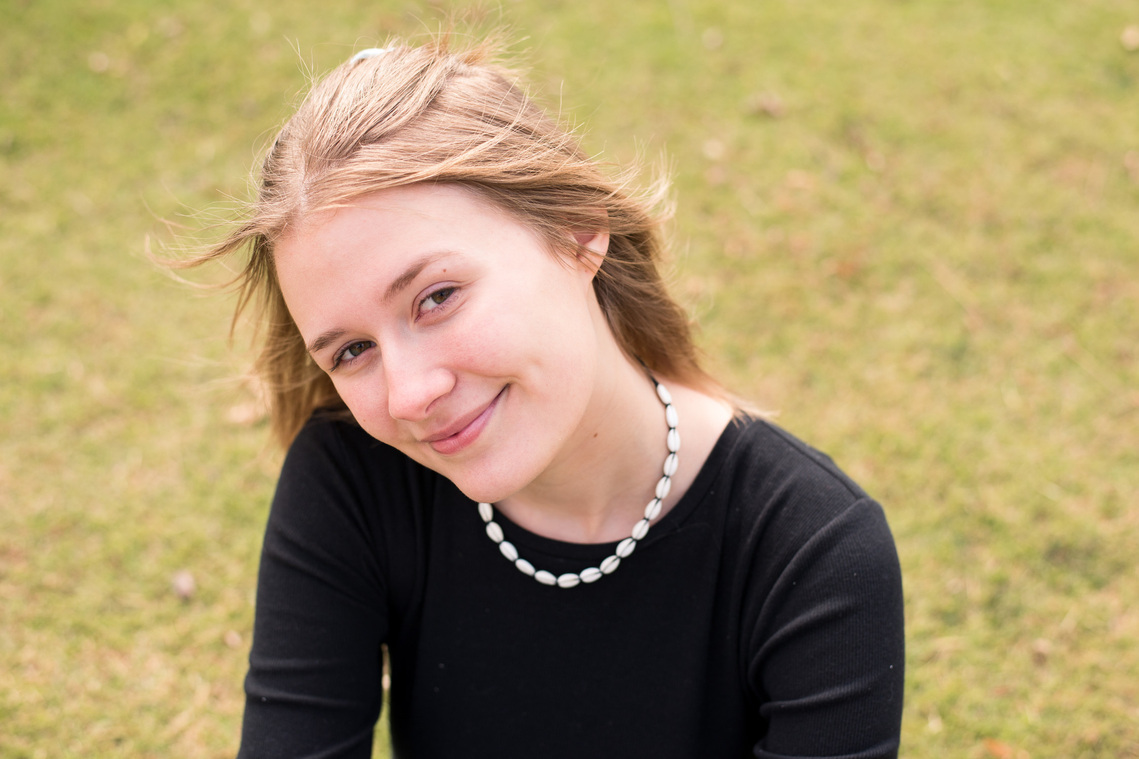 portrait of a teenage girl in a black shirt smiling sweetly at the camera