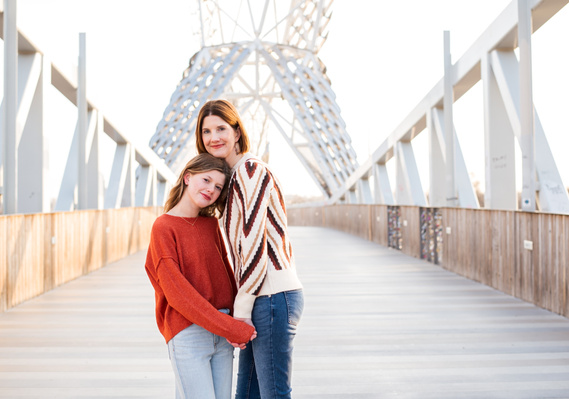 a mom and her teen daughter hold hands and hug together on the Skydance Bridge at Scissortail Park in Oklahoma City 