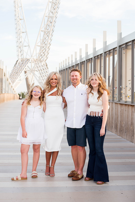parents stand hugging and smiling with their teen daughters on the Skydance Bridge at Scissortail Park in Oklahoma City