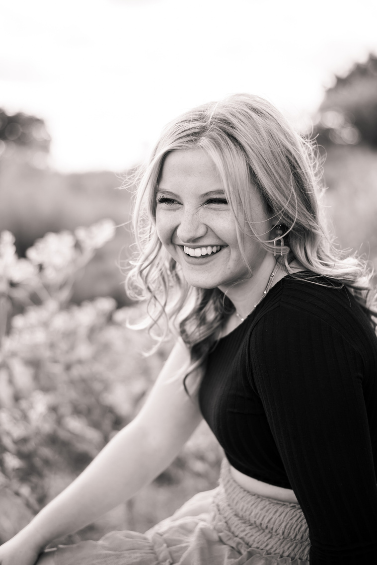 black and white photo of a high school senior girl looking to the side and laughing sweetly at her senior photo session in Oklahoma